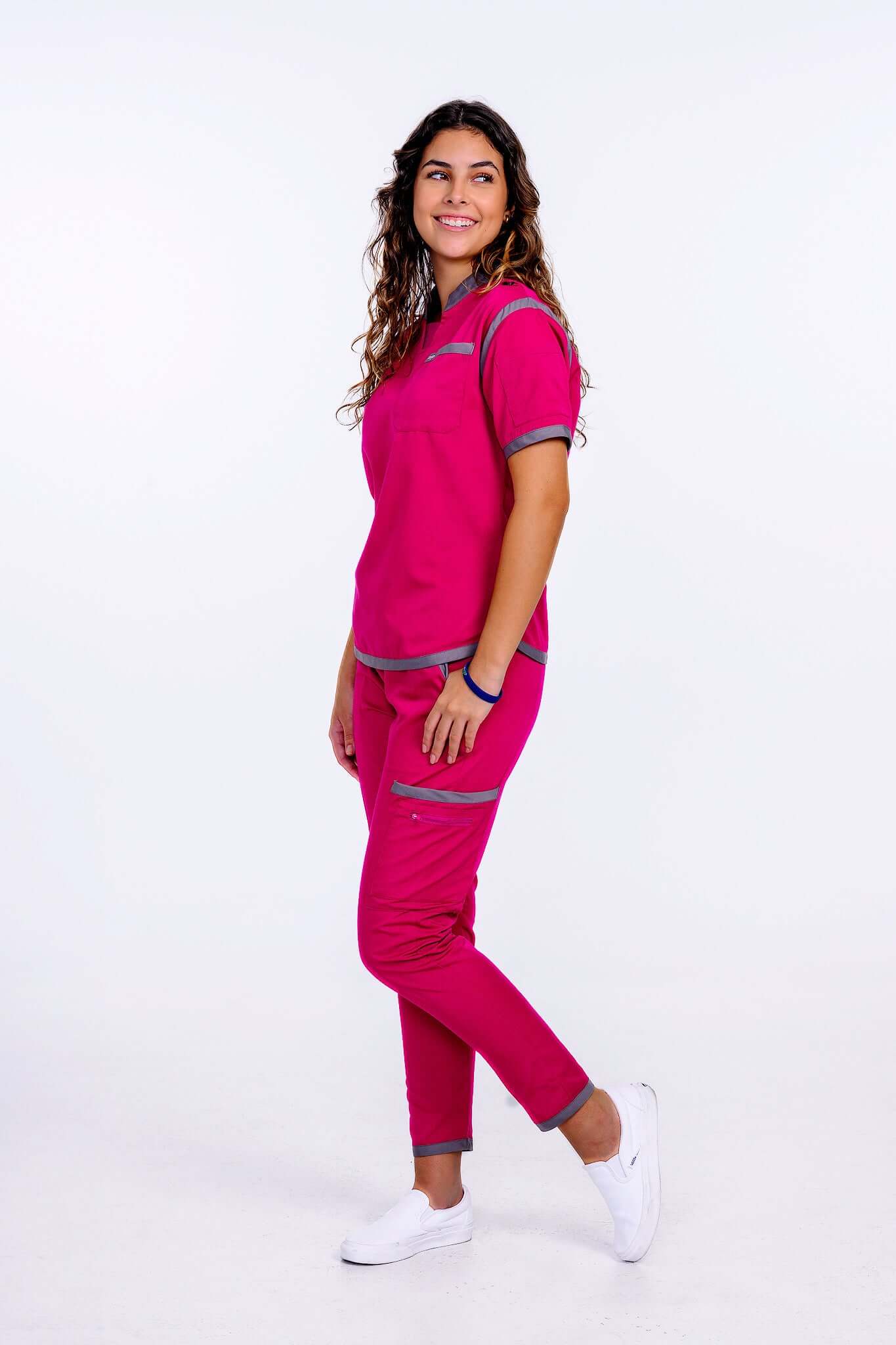 Woman in raspberry pink scrub top with gray trim, showcasing vibrant style and comfort in a healthcare setting.