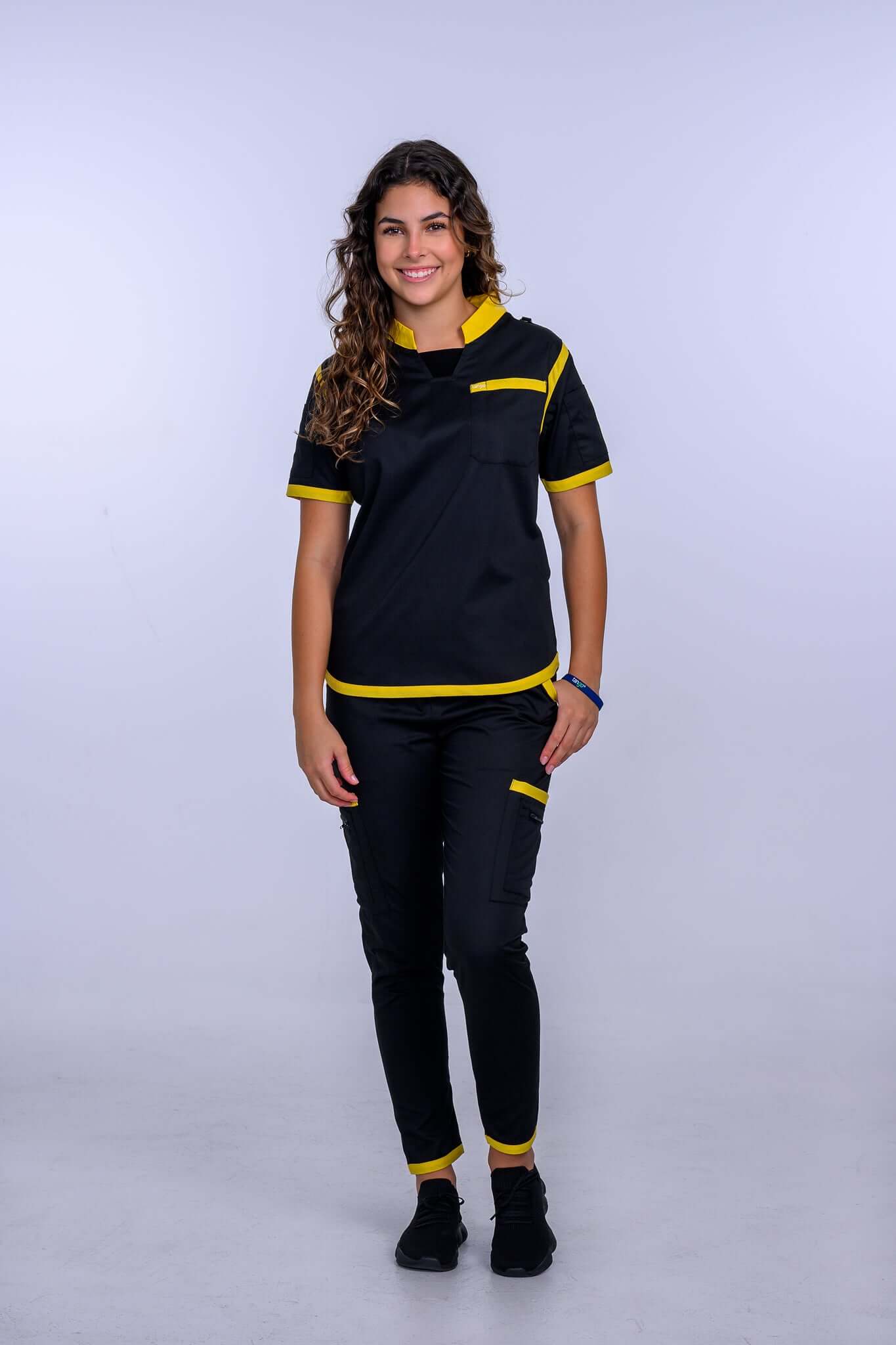 Woman wearing TangoScrubs Women's Jet Black / Yellow Scrub Pants set, showcasing sleek black design with yellow trim accents.